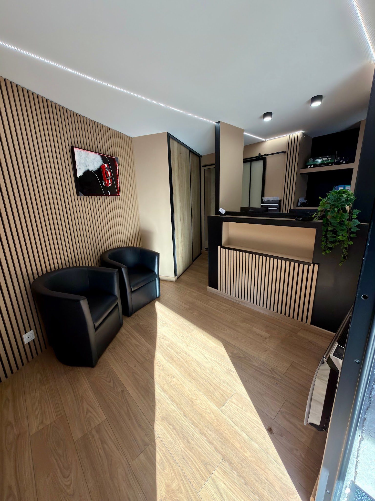 L'accueil du garage : fauteuils, comptoir et bardage bois